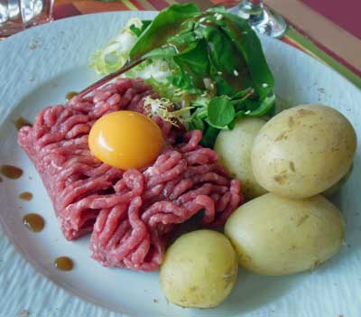 photo of steak tartar with raw egg yolk and new potatoes